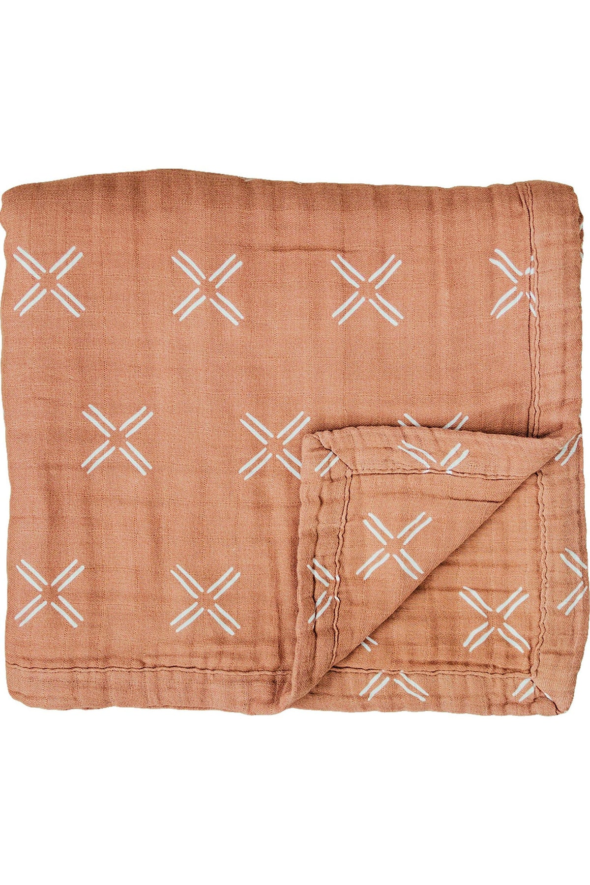 Peach-colored muslin quilt with white cross patterns, folded at one corner, showcasing its soft, layered texture.