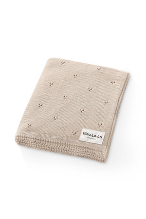 Beige knitted blanket with a pointelle pattern and a Bleu La La Organics label, folded neatly.
