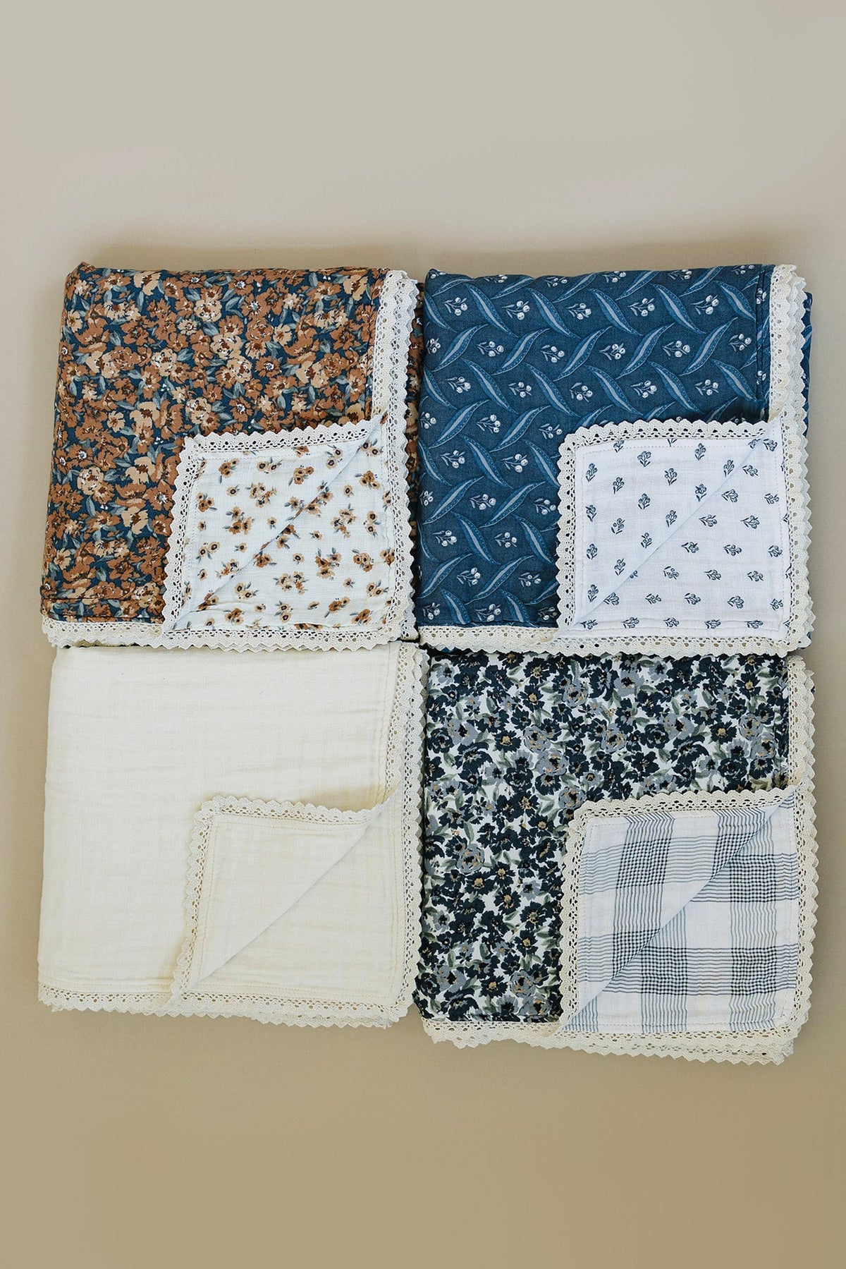 Four muslin quilts with lace edges, featuring floral and plaid patterns in blue, brown, and cream colors.