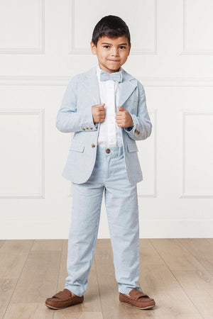 A young boy stands confidently in a light blue seersucker suit, complete with a bow tie and white shirt.