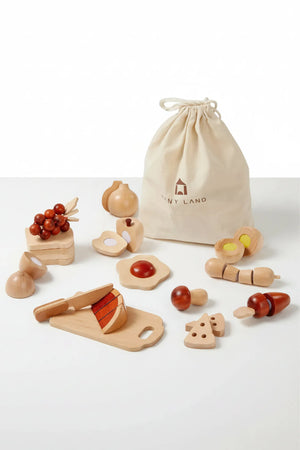 A wooden play food set featuring various colorful pieces like fruits, vegetables, and a cutting board, all stored in a beige drawstring bag with the logo Tiny Land.