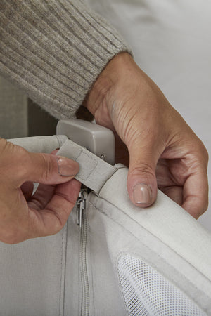 A close-up of a persons hands adjusting the fabric of a Shnuggle Air Lite Bedside Bassinet, showcasing its breathable mesh and sturdy construction, designed for newborn safety and comfort.