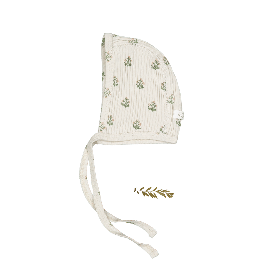 A soft, organic cotton baby bonnet features a textured cream fabric adorned with delicate green floral patterns. The bonnet includes ties for secure fitting and is perfect for newborns.