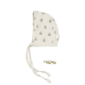A soft, organic cotton baby bonnet features a textured cream fabric adorned with delicate green floral patterns. The bonnet includes ties for secure fitting and is perfect for newborns.