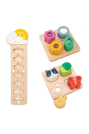 Wooden sensory toys include a rainmaker with tumbling beads and colorful shape blocks on square trays.