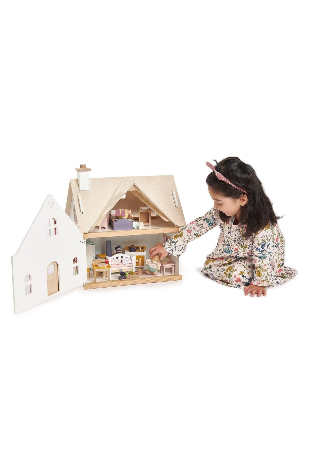A child plays with the Tender Leaf Cottontail Cottage dollhouse, which features a natural wood design and colorful interior accessories.
