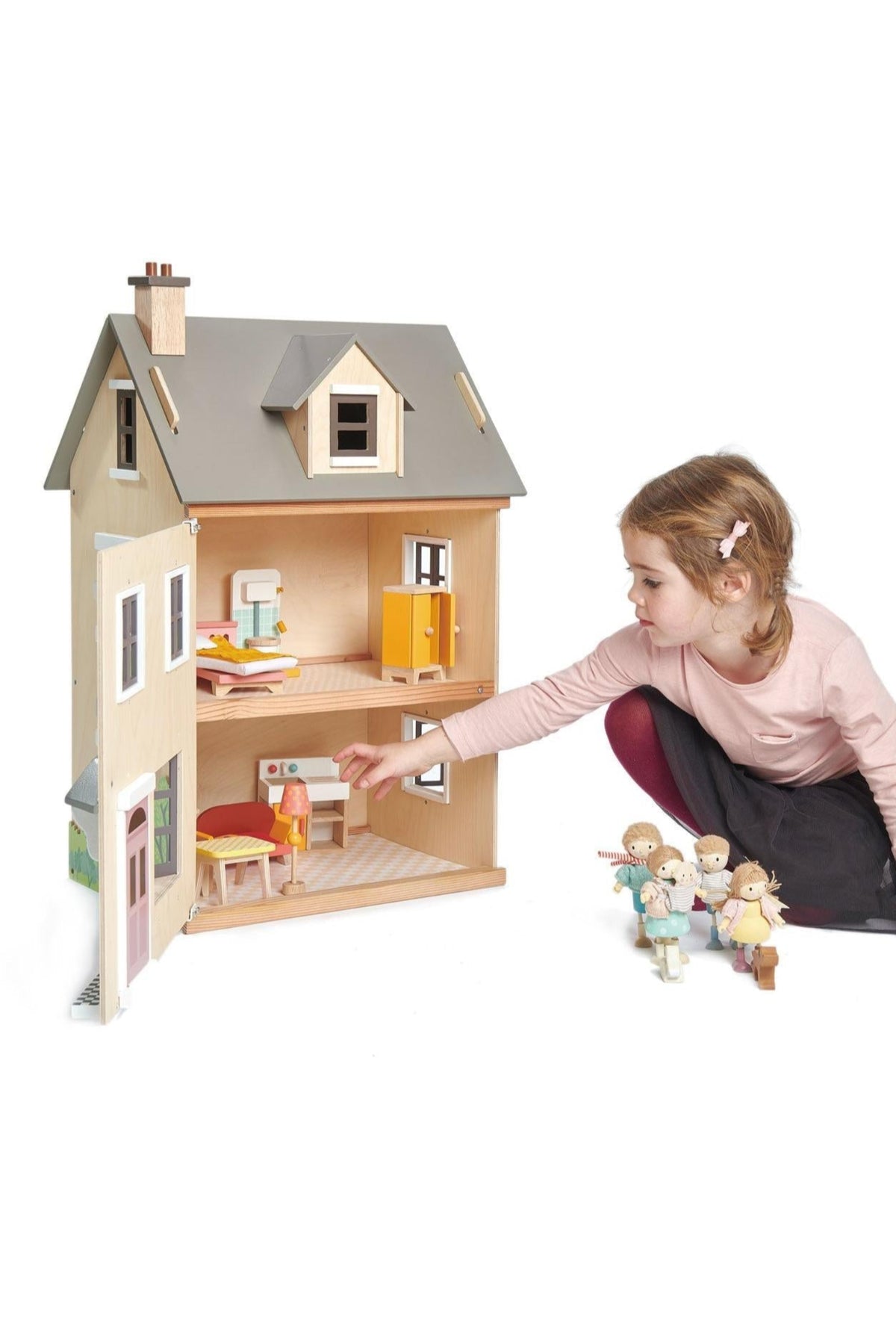 A child interacts with a wooden dollhouse, featuring a modern design and natural colors, alongside wooden figures.