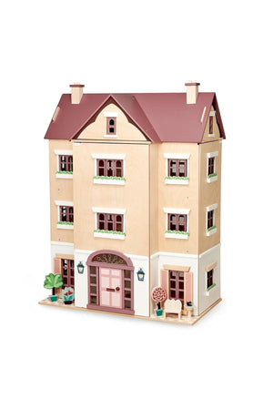 A wooden dollhouse in a traditional style, featuring a pink and beige exterior with detailed windows and a front porch. Ideal for imaginative play, it’s made from sustainable materials.