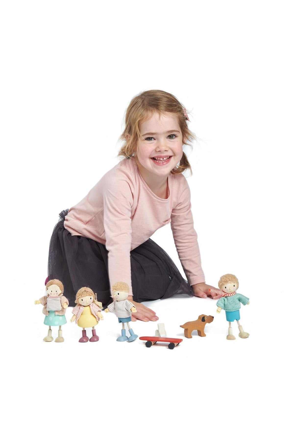 A young girl plays on the floor with the Tender Leaf Wooden Toys Goodwood Doll Family and a wooden cart.