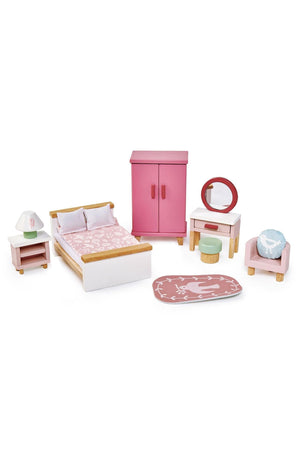 A colorful wooden dollhouse bedroom set featuring a pink bed with bedding, wardrobe, bedside table, lamp, dressing table, stool, and a printed rug, all designed for sustainable play.