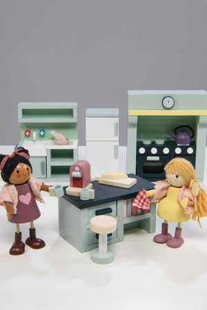 Toy kitchen set with two dolls in front of it on a white background