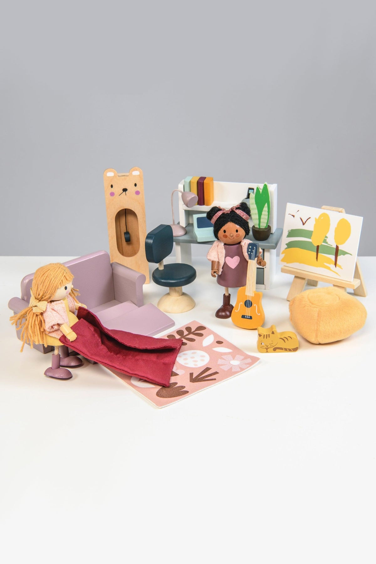 A colorful wooden dollhouse study furniture set featuring two dolls, a swivel chair, a couch, and an easel with a painting. The cozy scene encourages imaginative play for children.