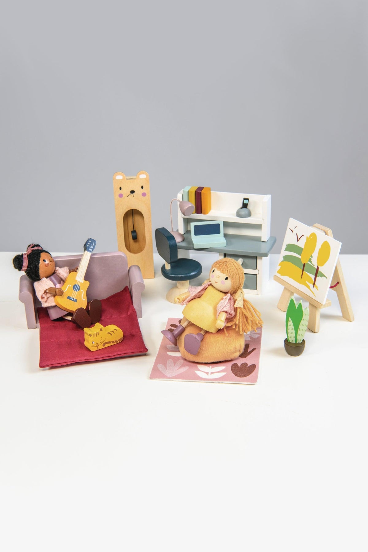 Two dolls sit in a cozy playroom, one strumming a guitar on a rug, while the other, dressed in a yellow apron.