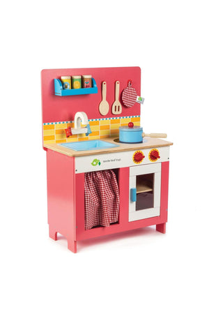 A vibrant wooden play kitchen in pink, featuring a sink, stove, and oven with red knobs. Designed by Tender Leaf Toys, its perfect for imaginative play for children aged three.