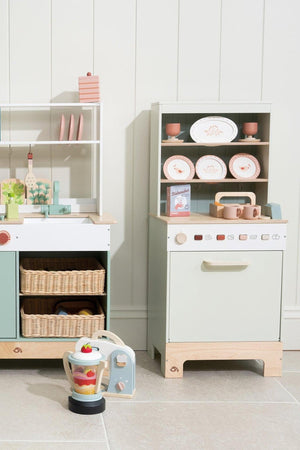 Children's play kitchen set with various toys including dishwasher and food blender on a light-colored floor.