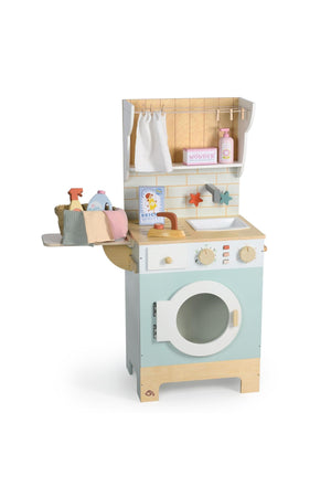 A colorful wooden laundrette playset featuring a washing machine with a white door, a countertop with accessories, and a charming wicker basket. Ideal for imaginative play and eco-conscious fun.