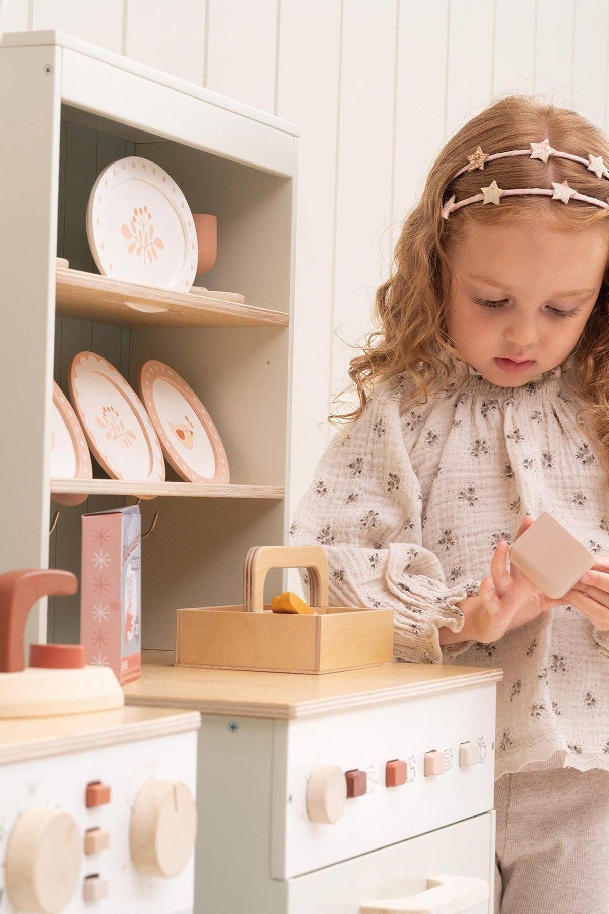 Child playing with toys in a play kitchen setting