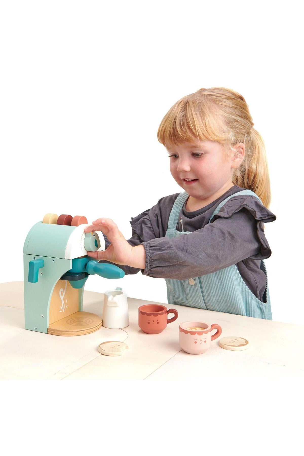 A child plays with the Tender Leaf Wooden Toys babyccino maker, featuring soft colors, coffee cups, and a milk jug.