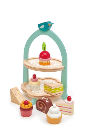 A colorful wooden afternoon tea stand features two tiers with various toy desserts, including cakes and cupcakes, along with a charming blue bird on top. Ideal for imaginative play.