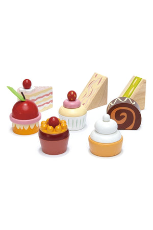 Colorful wooden toy desserts from Tender Leaf, featuring cupcakes, a chocolate roll, and a slice of cake. These eco-friendly toys are designed for children ages 3 and up.