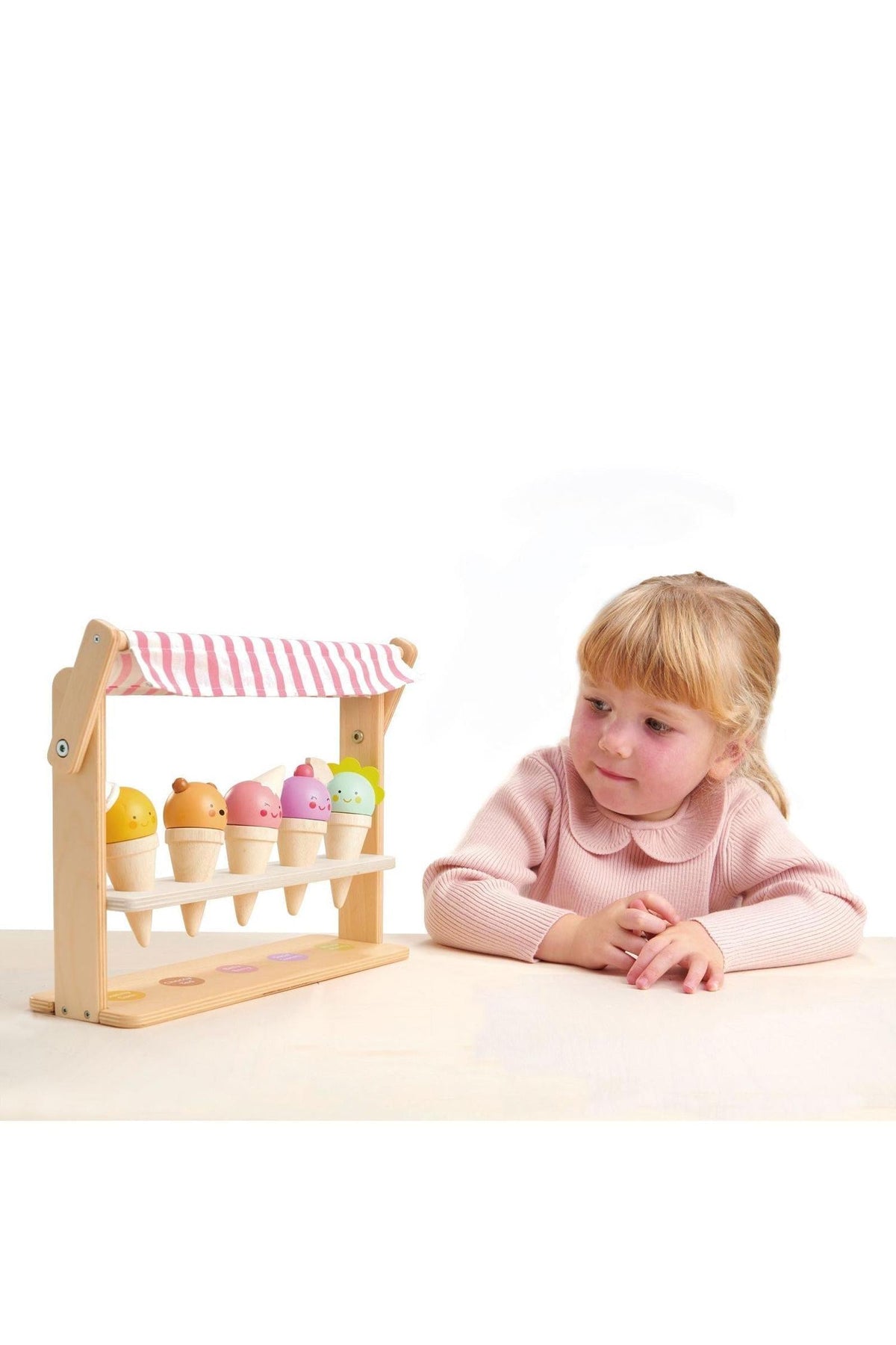 A child interacts with a wooden ice cream shop featuring five colorful cones, each with a friendly face.
