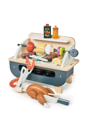 A colorful wooden barbeque play set features a self-standing grill with various accessories, including sausages, a chicken, vegetables, and pretend sauce bottles, all crafted from eco-friendly materials.