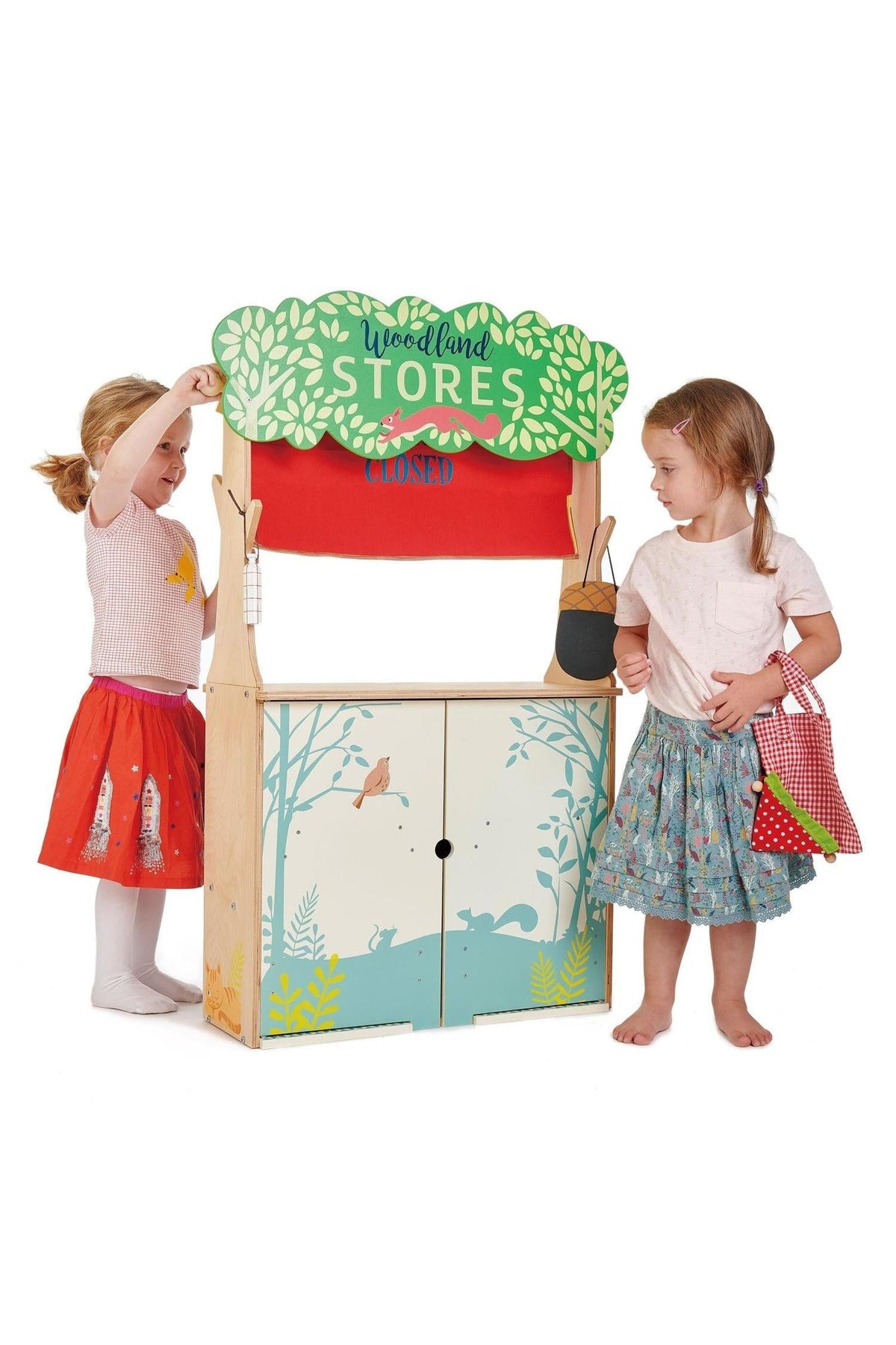 Two children play with the Tender Leaf Woodland Stores playset, featuring a wooden structure and colorful illustrations.
