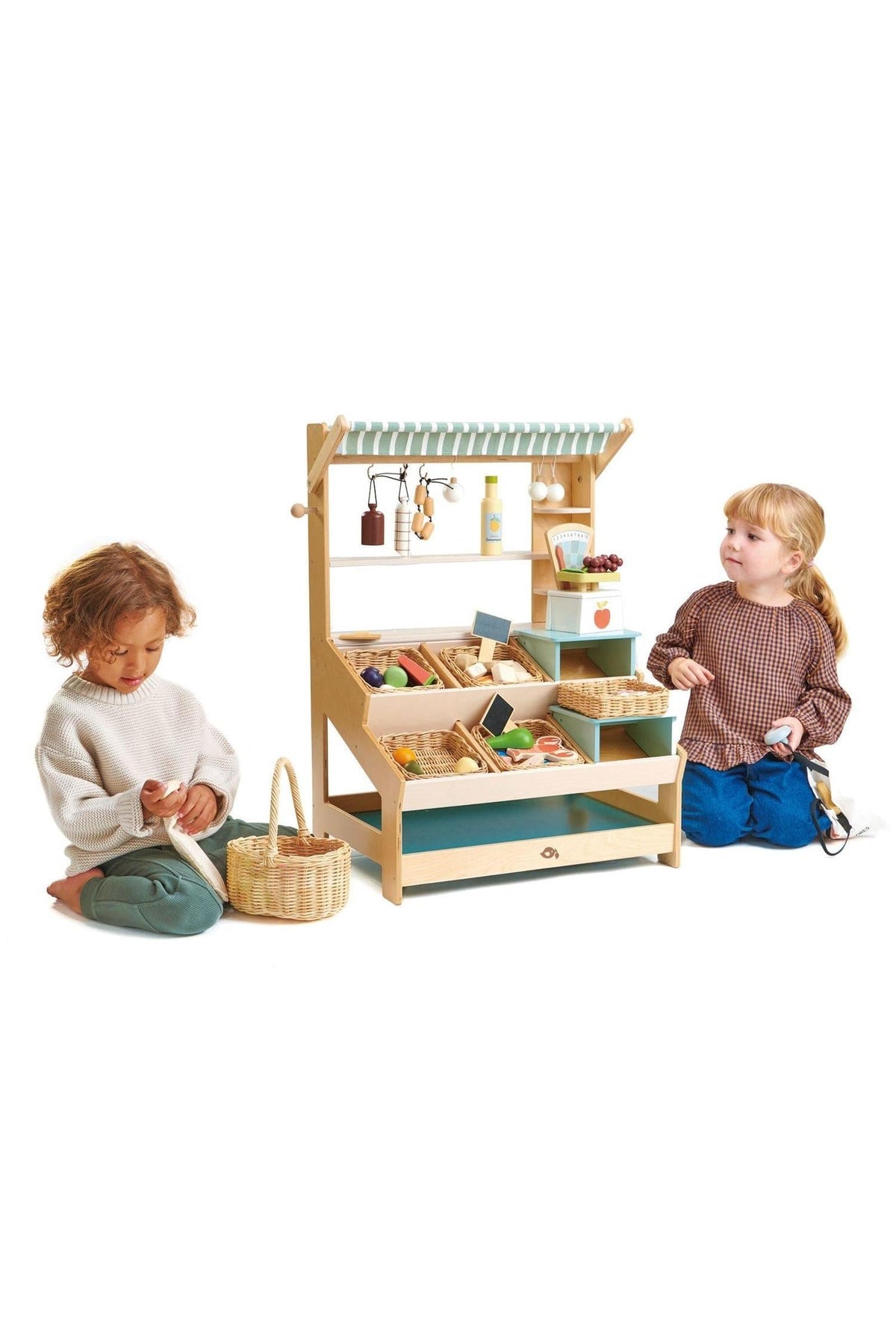Two children play with a wooden market stall filled with pretend food items, showcasing its colorful shelves and eco-friendly design.