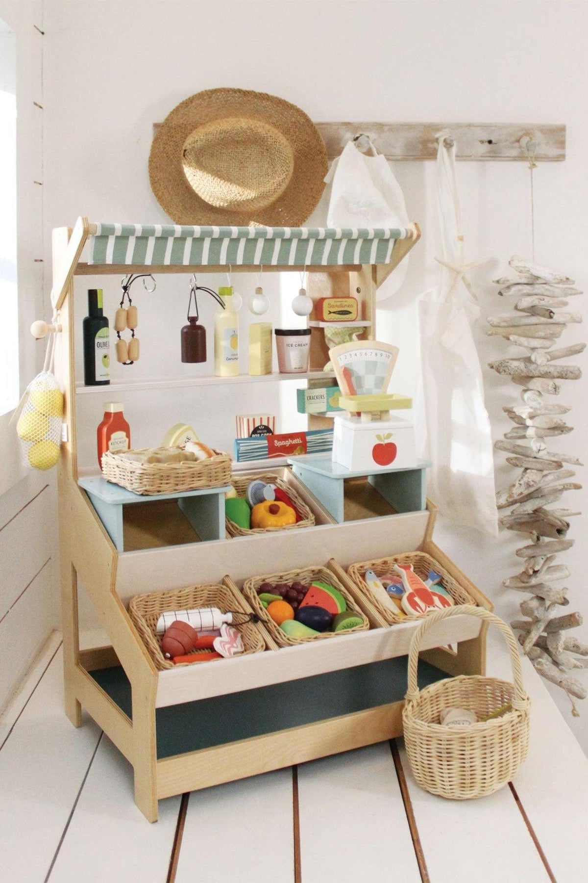 A wooden market stall features shelves filled with colorful toy produce and grocery items, designed for imaginative play.
