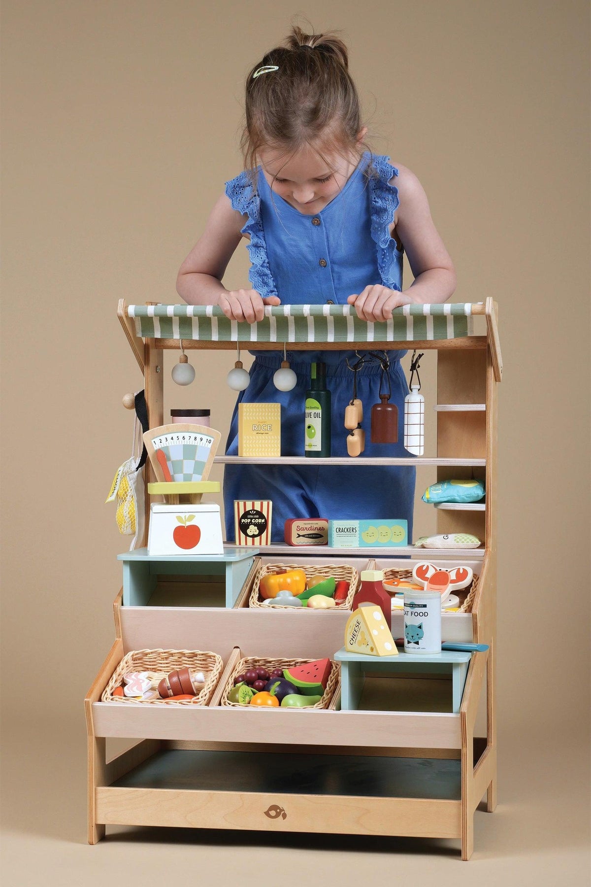 A child interacts with a wooden market stall filled with colorful pretend food and accessories, showcasing sustainable craftsmanship.