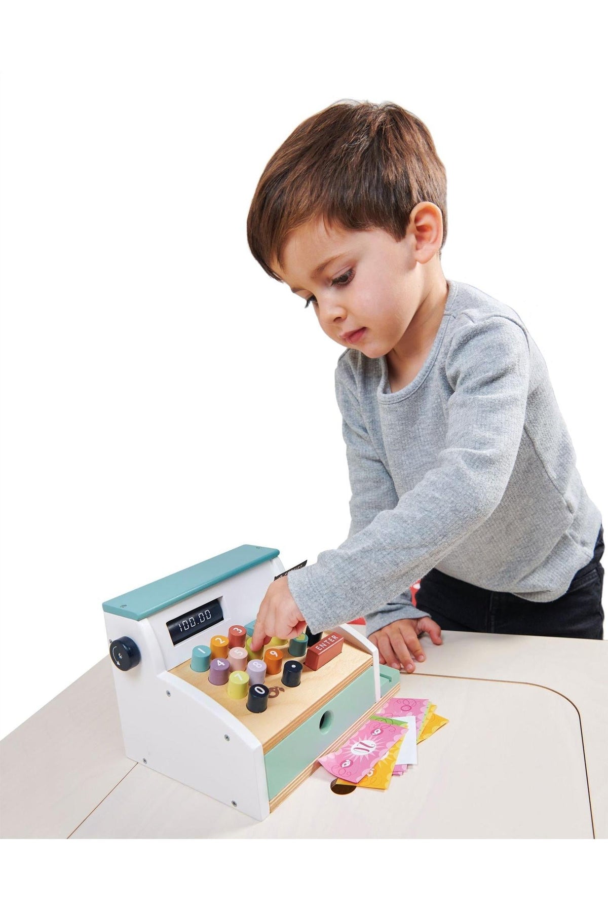 A child plays with a colorful wooden cash register, pressing buttons and engaging in imaginative play.