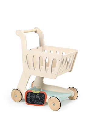 A light wooden shopping cart with a fabric base and apple-shaped chalkboard, designed for children’s imaginative play.