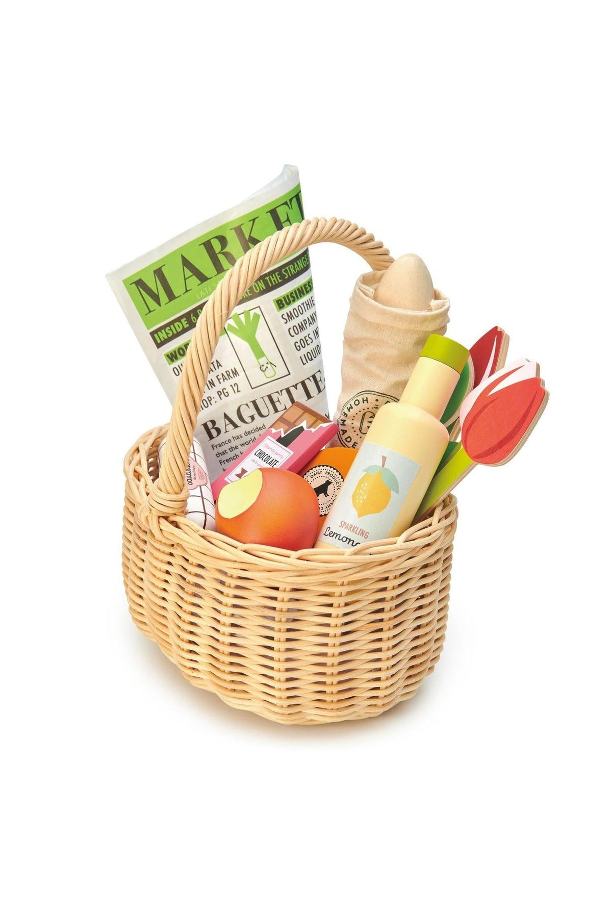 A wicker shopping basket filled with colorful wooden play food items, including a baguette, fruit, and tulips.