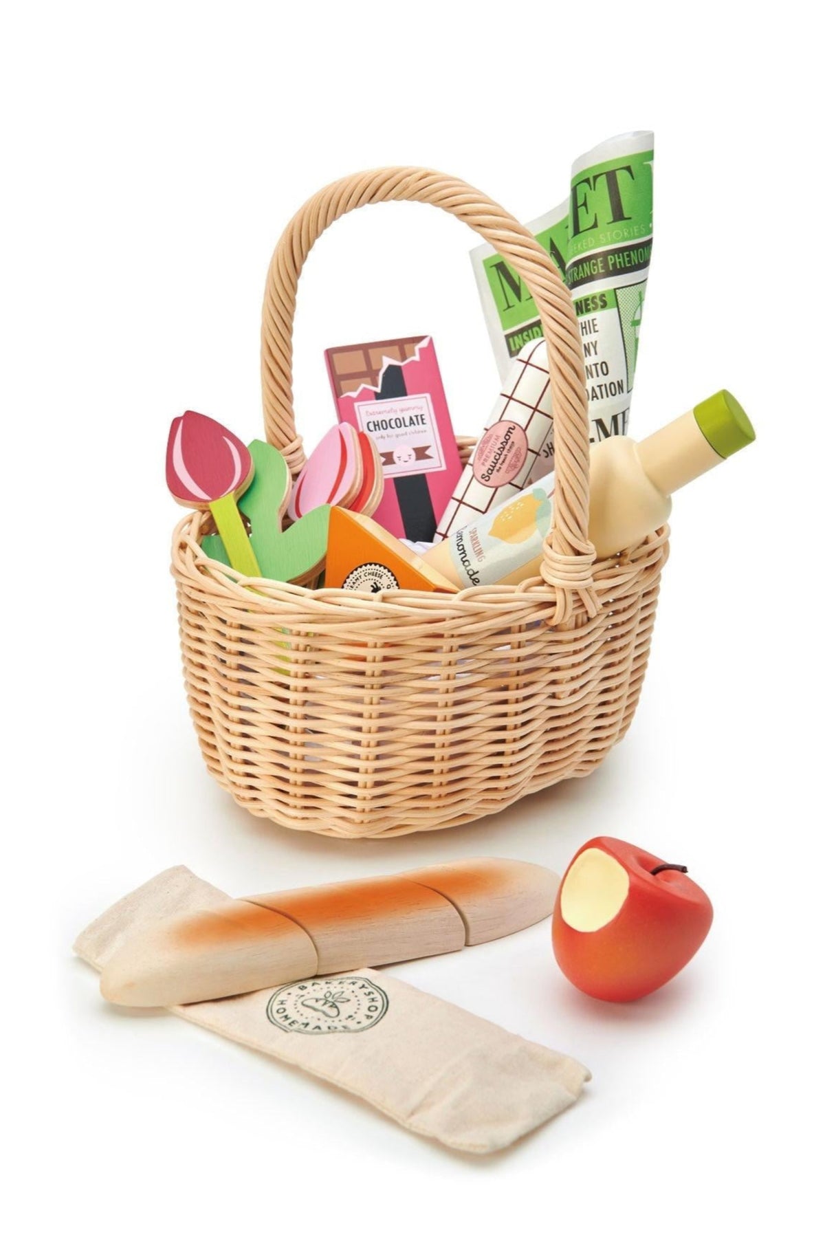 A wicker shopping basket filled with colorful wooden food items, including a chocolate bar, lemonade bottle, and tulips.