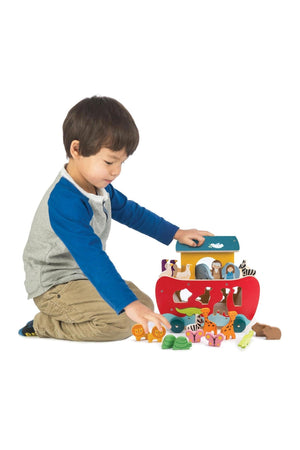 Child playing with a toy Noah's Ark on a white background