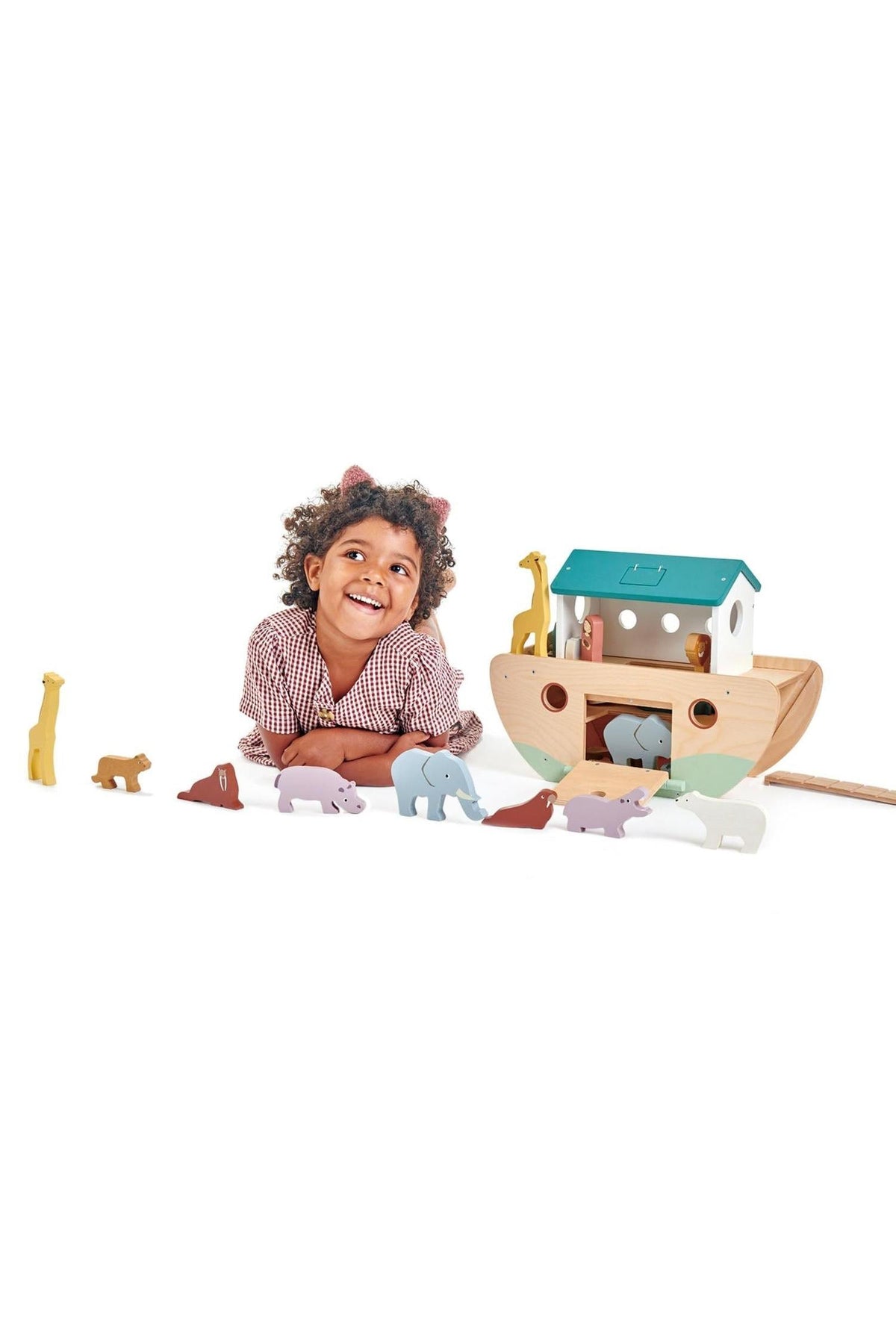 A smiling child plays with a wooden ark toy, surrounded by colorful animal figures.