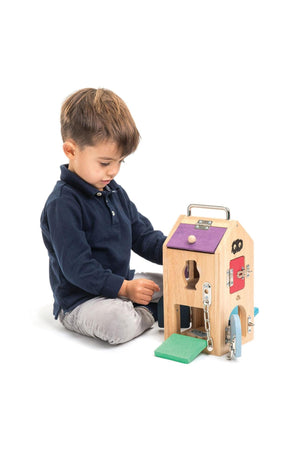 A young child interacts with a colorful wooden Monster Lock Box, featuring various locking mechanisms and vibrant designs.