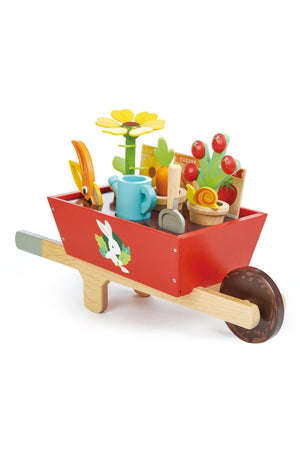 A colorful wooden wheelbarrow set features a red wheelbarrow filled with flower pots, a watering can, and gardening tools.