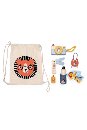 A beige drawstring bag features a lion graphic, surrounded by wooden safari adventure items including a camera, water bottle, and compass, all designed for imaginative play.