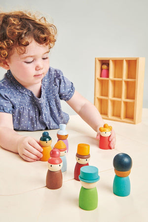 A child with curly hair plays with colorful wooden figures on a table, showcasing the Tender Leaf Happy Folk Hotel.