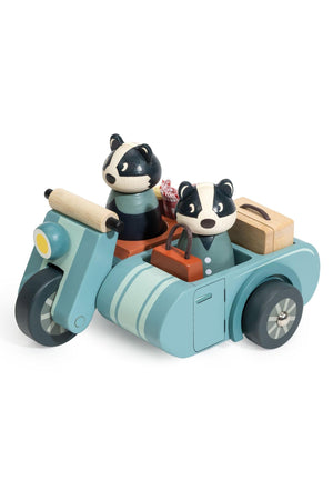 A charming wooden motorbike toy features two badger characters in a sidecar, complete with a picnic basket and stylish blue and mint green design.