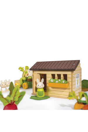 A charming wooden playset featuring a cozy shed, a bunny figure, and colorful vegetable pieces, promoting imaginative gardening play.