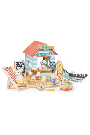 A colorful wooden beach hut toy set features Sandy the seagull, a deck chair, and various food items, promoting imaginative.