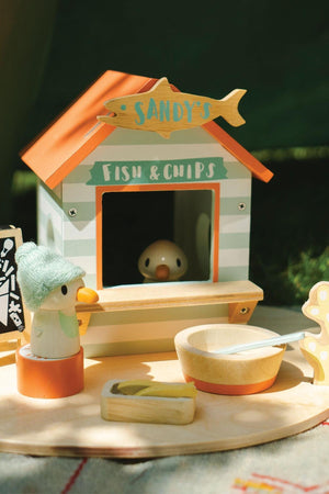 Colorful wooden beach hut playset features Sandy the seagull, a fish and chips stall, and various accessories.