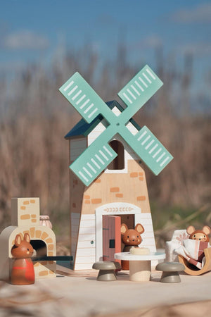 A colorful wooden playset features a two-story windmill with green blades, accompanied by three adorable field mice figures. This charming toy encourages imaginative play and is made from sustainable materials.