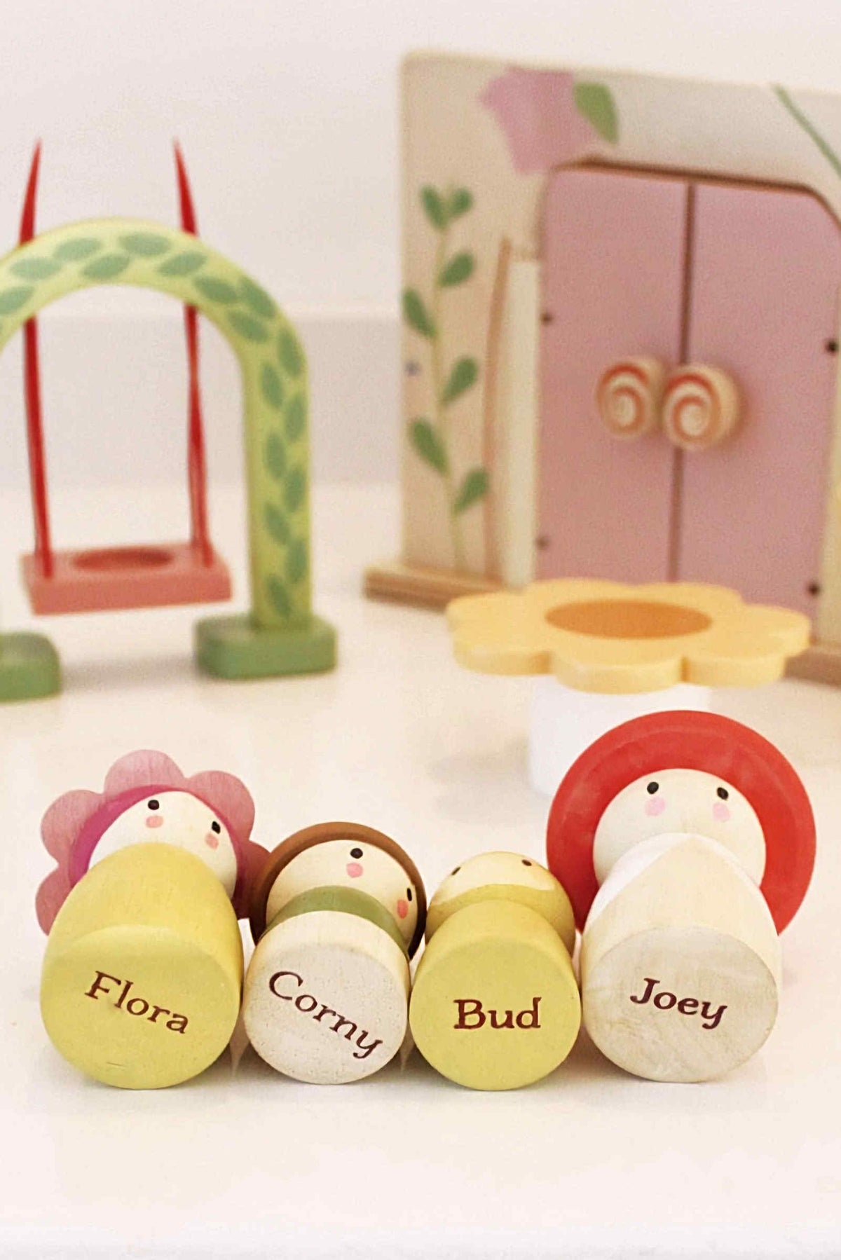 A set of four wooden character toys named Flora, Corny, Bud, and Joey, featuring colorful designs and friendly faces.