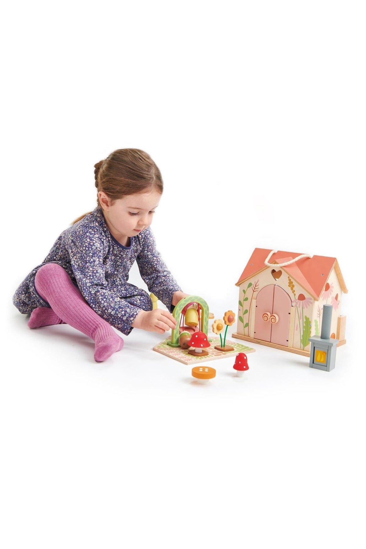 A child plays with the Tender Leaf Wooden Toys Rosewood Cottage set, featuring colorful mushrooms and flowers, enhancing imaginative play.