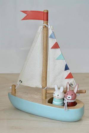 A wooden sailboat features two charming animal friends, a rabbit and a mouse, with colorful bunting and fabric sails.