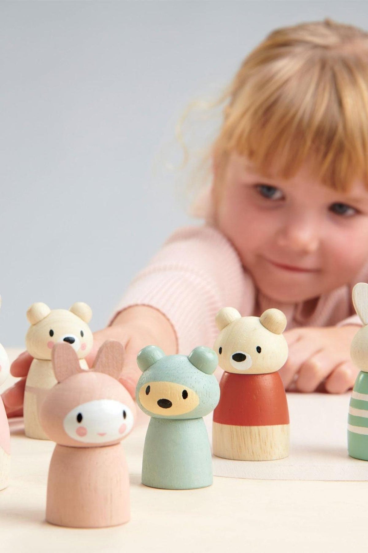 A child interacts with colorful wooden animal figurines, including bunnies and bears, showcasing the Tender Leaf Toys collection.