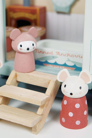 Two charming wooden mouse figurines in pink and red polka dots stand at the steps of a colorful shepherd’s hut, crafted from sustainable materials, designed for imaginative play.